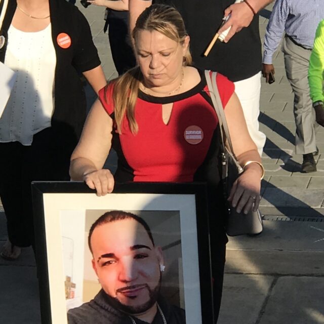 Aleida holds an image of her son Alex