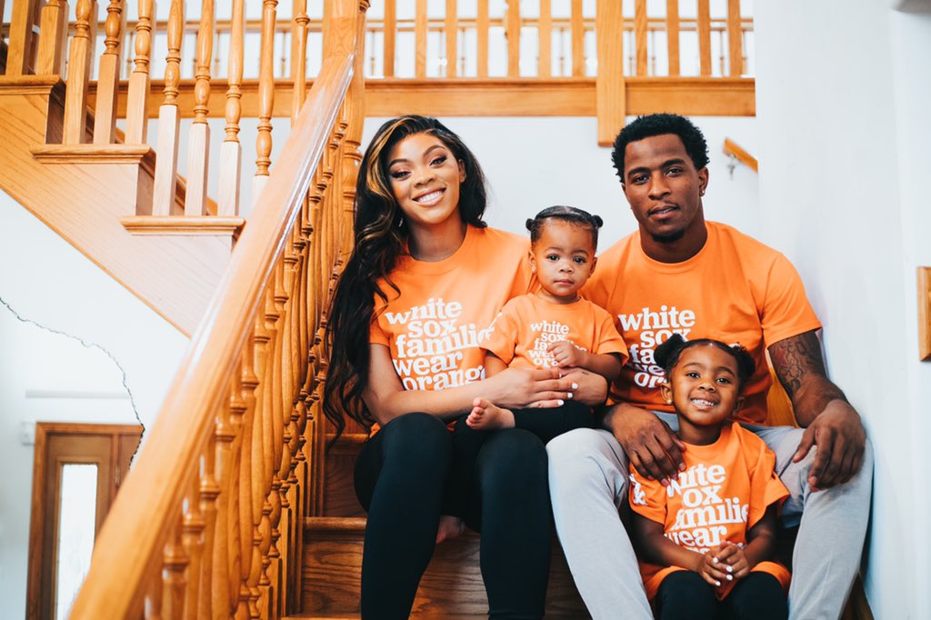 Baseball player Tim Anderson and his family smile together while wearing orange at home