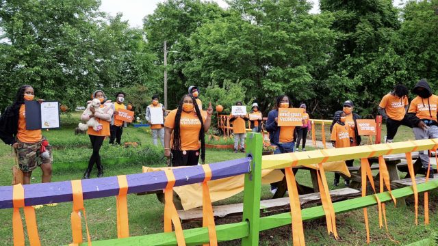 A group of volunteers stands at a remembrance garden for victims of gun violence