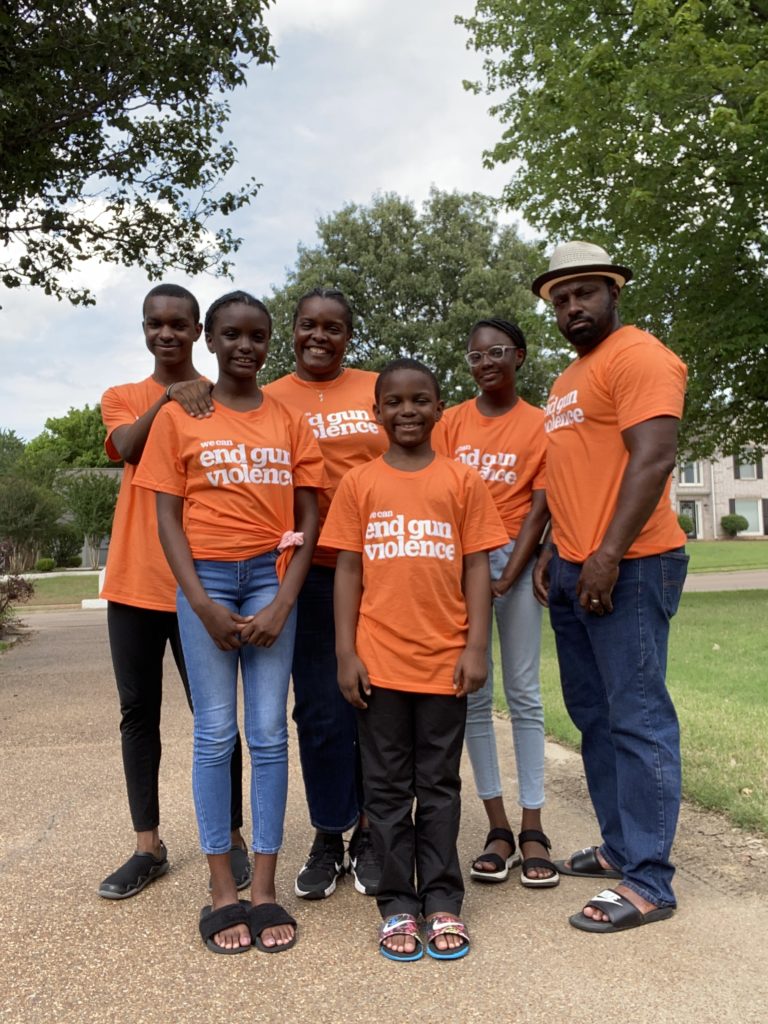 A group of six people wearing orange t-shirts with the words "We can end gun violence"