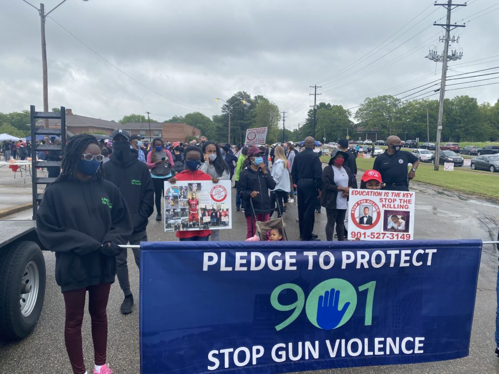 A group of people marching down a street holding signs protesting gun violence