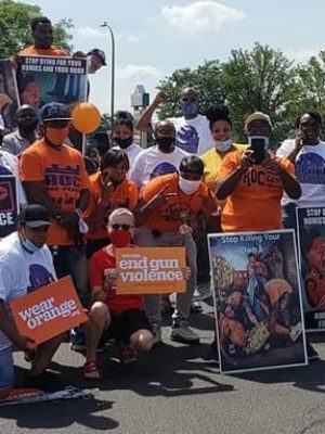 A group of people holding up Wear Orange signs at an event