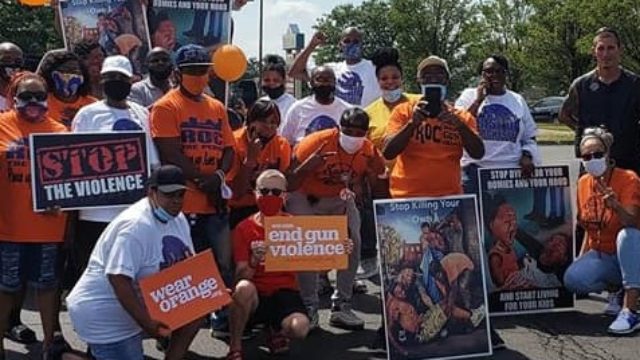 A group of people holding up Wear Orange signs at an event