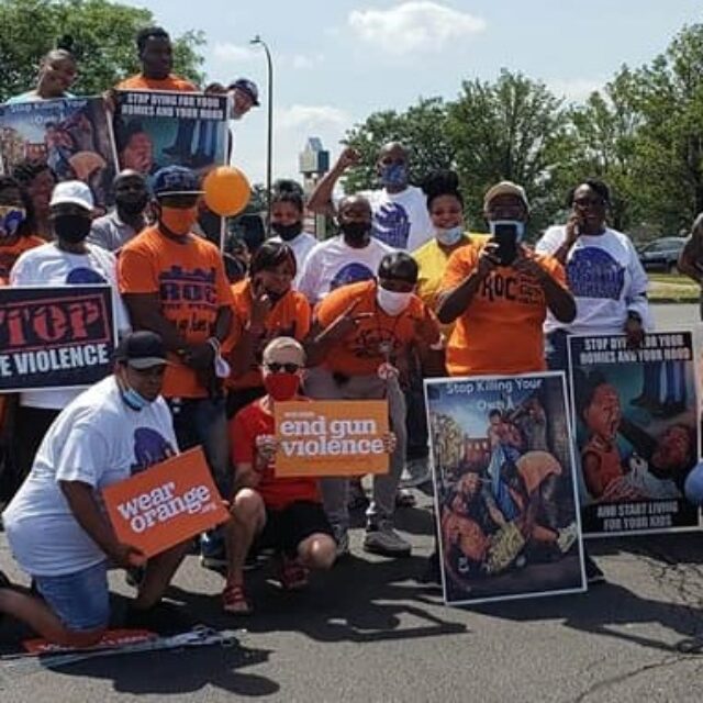 A group of people holding up Wear Orange signs at an event