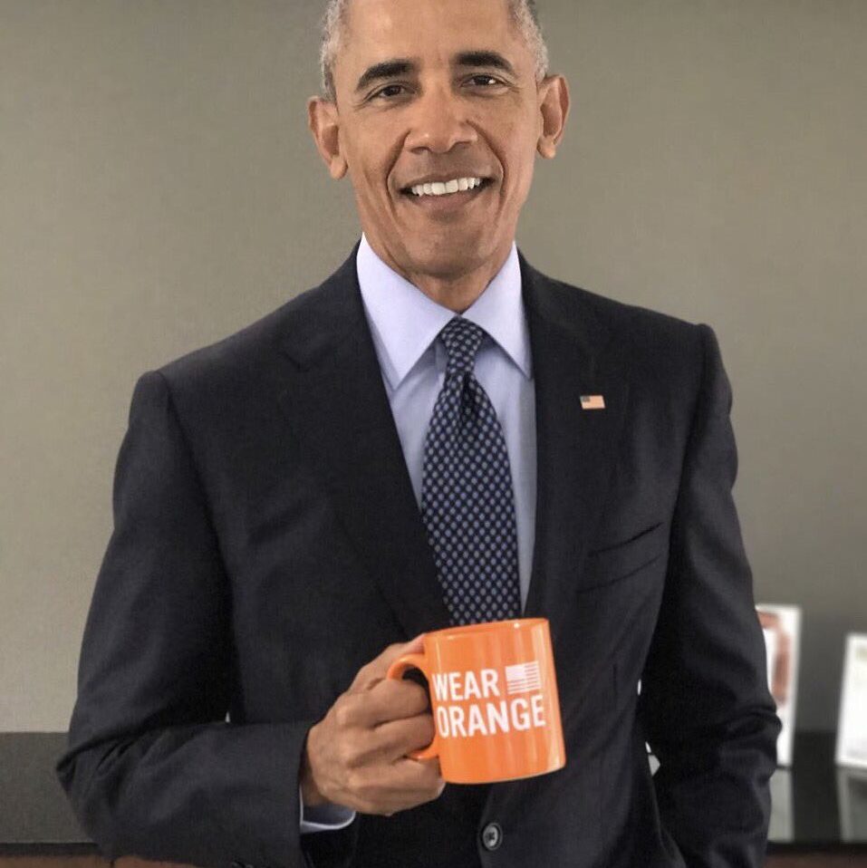 President Barrack Obama smiles while holding a Wear Orange mug