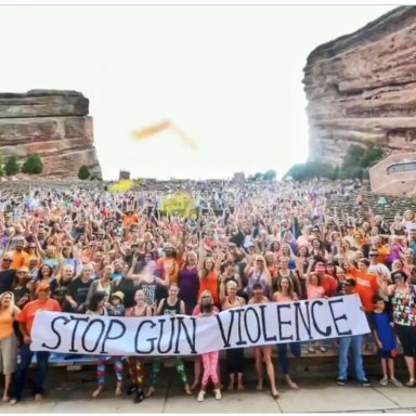 Wear Orange volunteers gather behind a "Stop Gun Violence" sign
