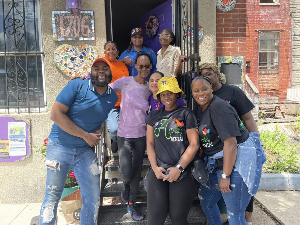 Dorian smiles with a group of 8 volunteers outside of their building in Baltimore
