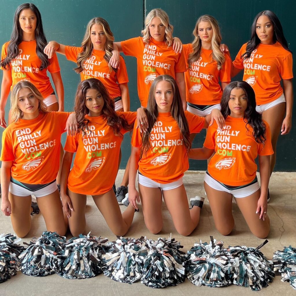 Philadelphia Eagles cheerleaders wearing orange EndPhillyGunViolence.com t-shirts