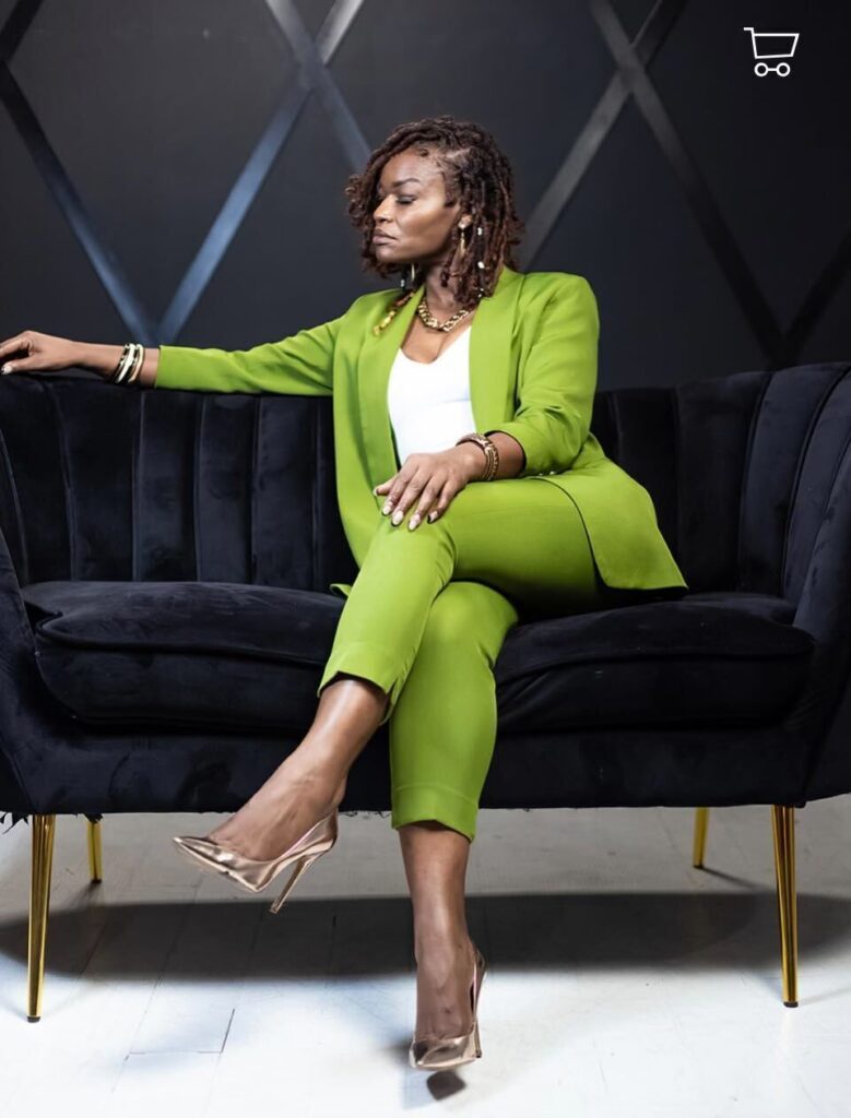 Lolita Frazier seated on a black velvet sofa, wearing a lime green pantsuit