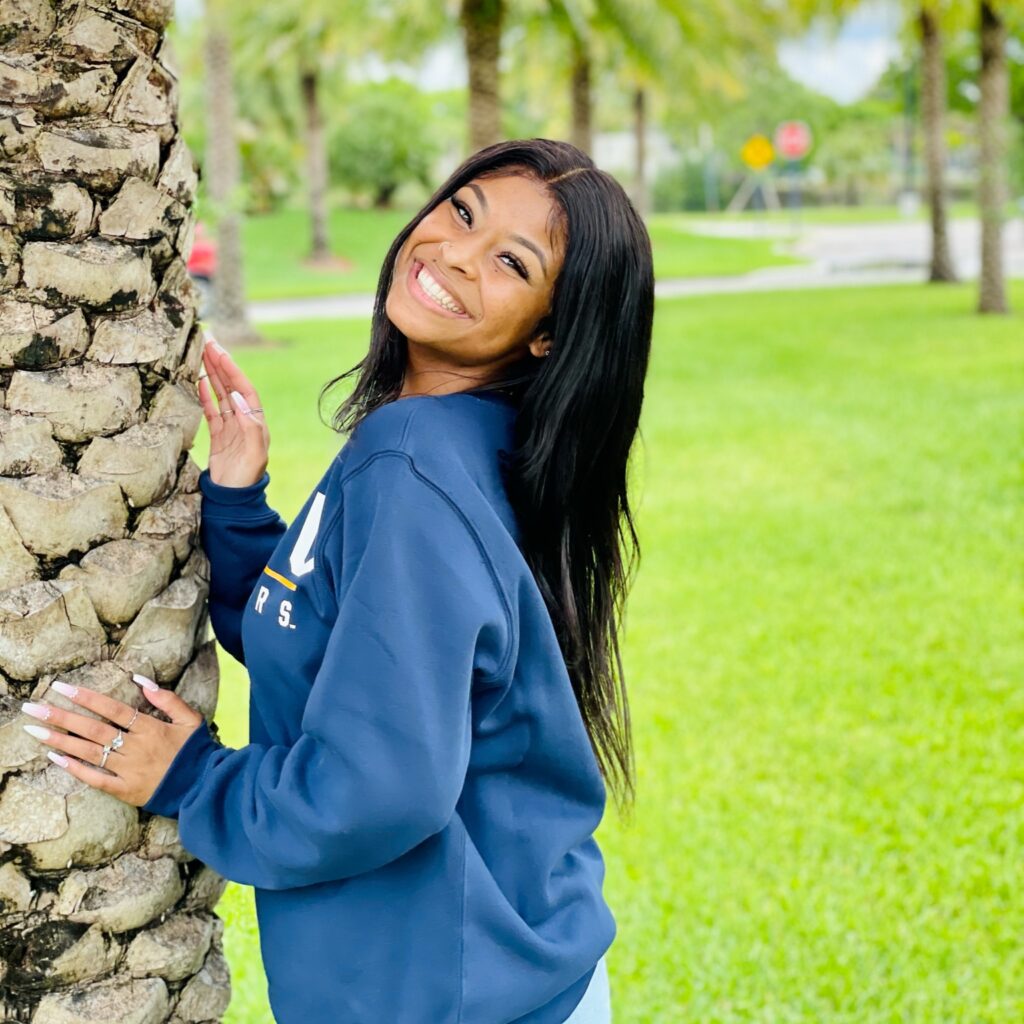 Taina Patterson smiling next to a palm tree