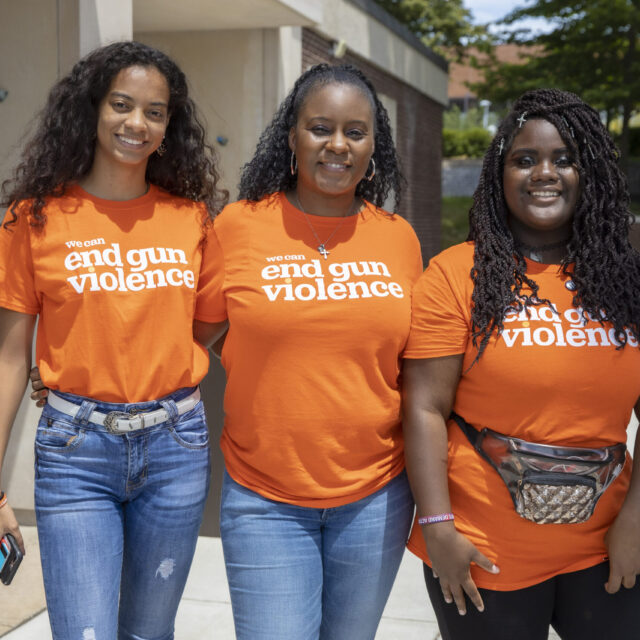 Three women wearing orange “we can end gun violence” t-shirts