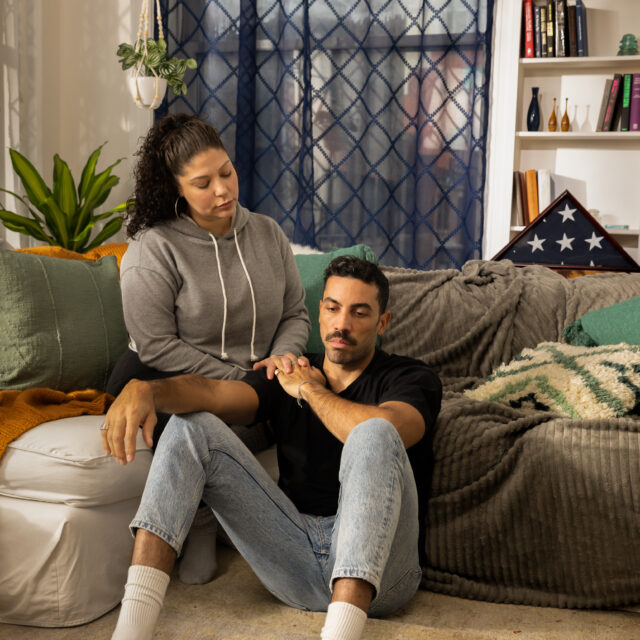 A woman comforts a man on a couch