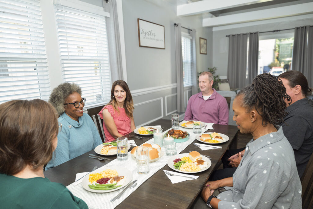 A group of people gather a table to share a meal together.